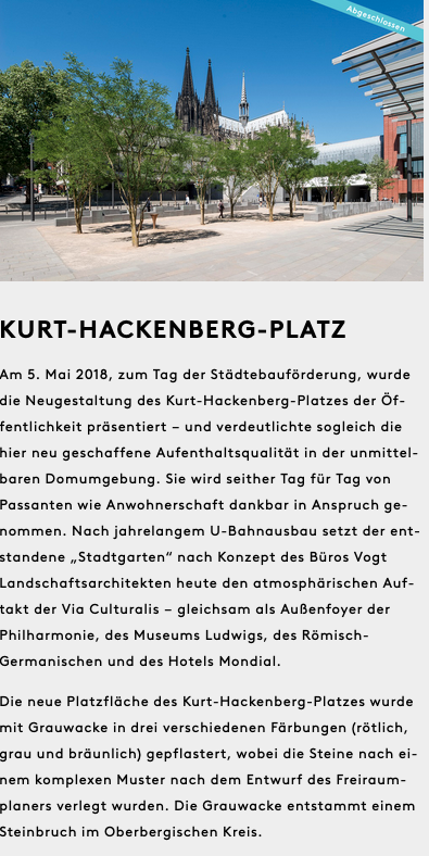 Ausschnitt eines Artikels. Ein Bild stellt den neu gestalteten Platz mit Bäumen und Sitzflächen dar, im Hintergrund sind die Domspitzen zu sehen.
»Am 5. Mai 2018, zum Tag der Städtebauförderung, wurde
die Neugestaltung des Kurt-Hackenberg-Platzes der Öffentlichkeit präsentiert — und verdeutlichte sogleich die
hier neu geschaffene Aufenthaltsqualität in der unmittelbaren Domumgebung. Sie wird seither Tag für Tag von
Passanten wie Anwohnerschaft dankbar in Anspruch genommen. Nach jahrelangem U-Bahnausbau setzt der entstandene „Stadtgarten" nach Konzept des Büros Vogt
Landschaftsarchitekten heute den atmosphärischen Auftakt der Via Culturalis — gleichsam als Außenfoyer der
Philharmonie, des Museums Ludwigs, des Römisch-
Germanischen und des Hotels Mondial.

Die neue Platzfläche des Kurt-Hackenberg-Platzes wurde
mit Grauwacke in drei verschiedenen Färbungen (rötlich, grau und bräunlich) gepflastert, wobei die Steine nach einem komplexen Muster nach dem Entwurf des Freiraumplaners verlegt wurden. Die Grauwacke entstammt einem
Steinbruch im Oberbergischen Kreis.«